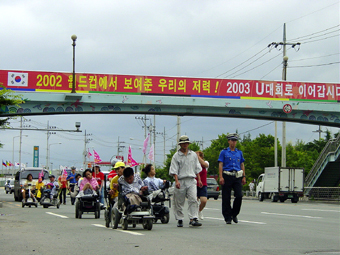 전동휠체어 도보행진에 나선 장애우들 장애우 정책과 현수막이 대조적이다